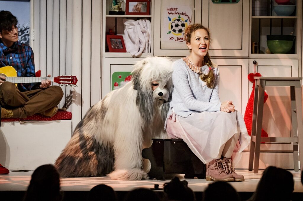 Paula kuschelt mit Hund Muffin im Musical Die Weihnachtsbäckerei