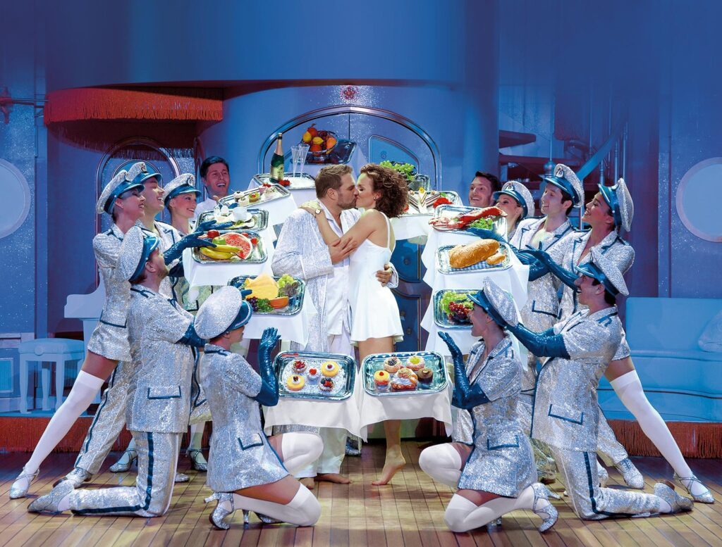 Ein Paar küsst sich umringt von Stewards im Musical ICH WAR NOCH NIEMALS IN NEW YORK